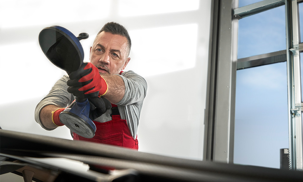 A man installing a new windscreen in a car
