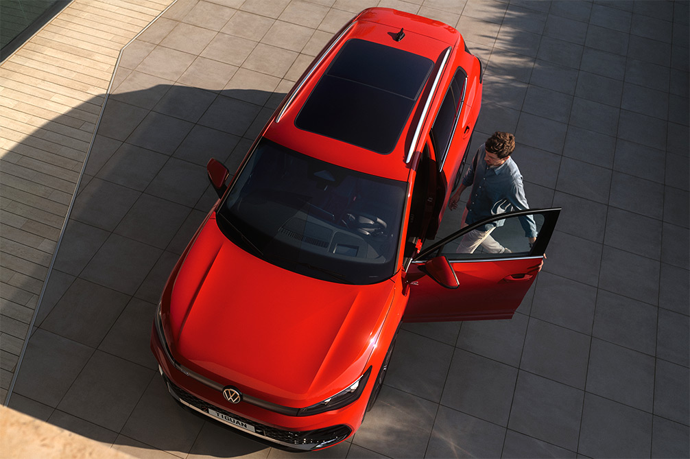 Top down view of a shiney Orange SUV with a man getting in the door