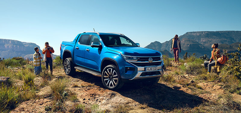 A family standing around a Blue Amarok Ute