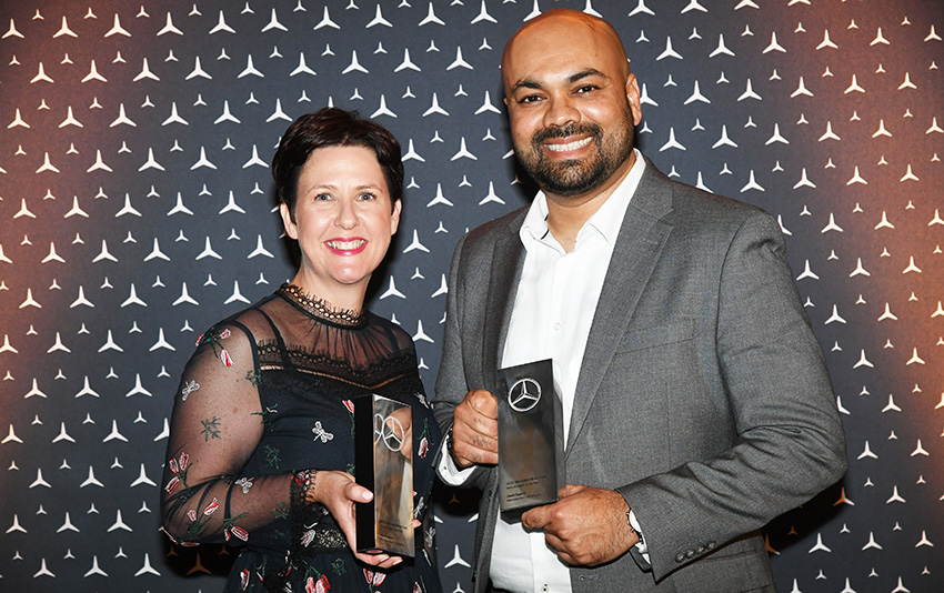 A man holding a mercedes-benz award standing next to a woman