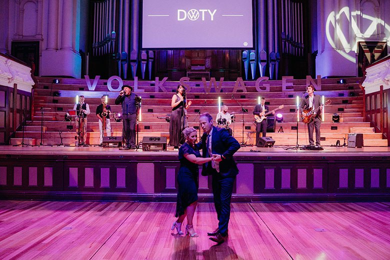 A couple dancing infront of a live band in a conert hall