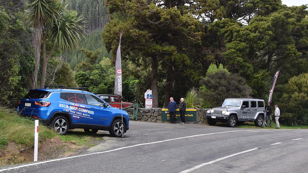 Blue Mitsubishi Outlander on paved road with mountains in the background