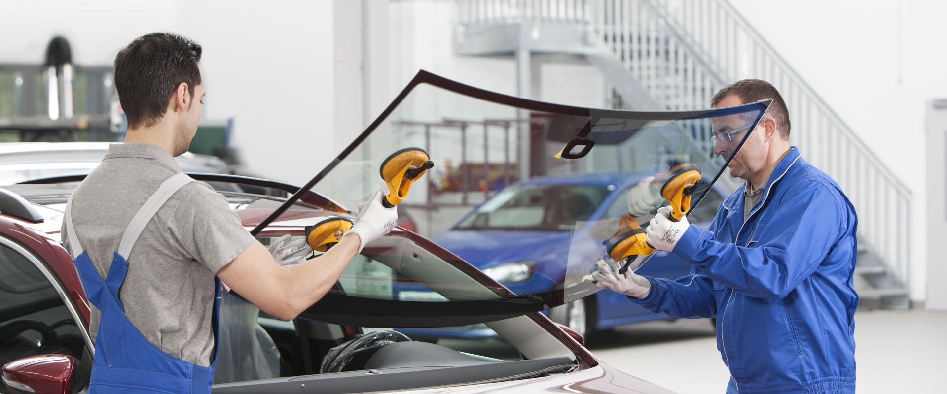 Two men securing a new windscreen on a car